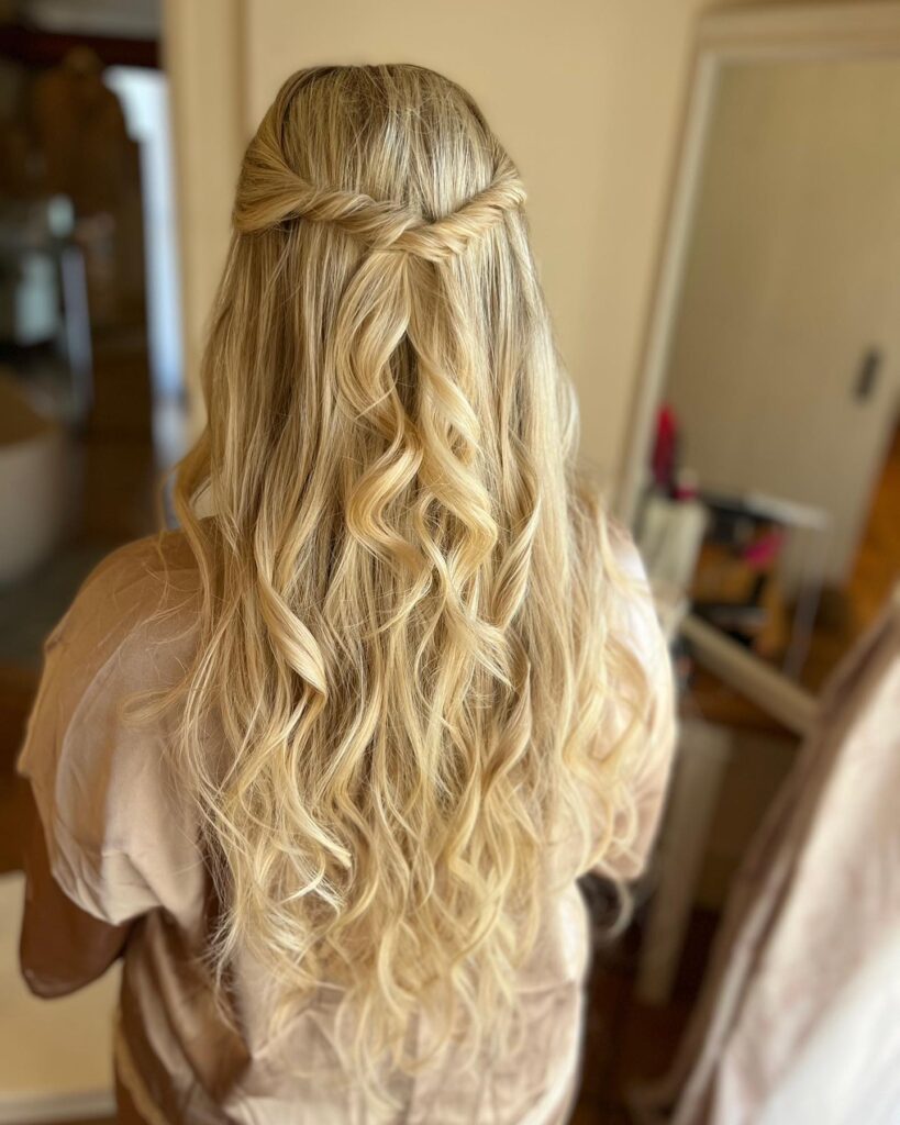 Long blonde wavy hair styled in a half up twist with loose flowing waves.