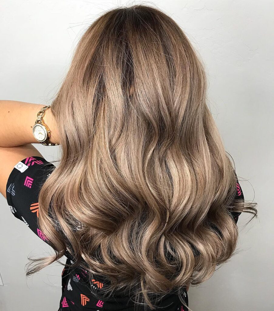 Long layered hair with soft glam waves and blended dimensional color tones.