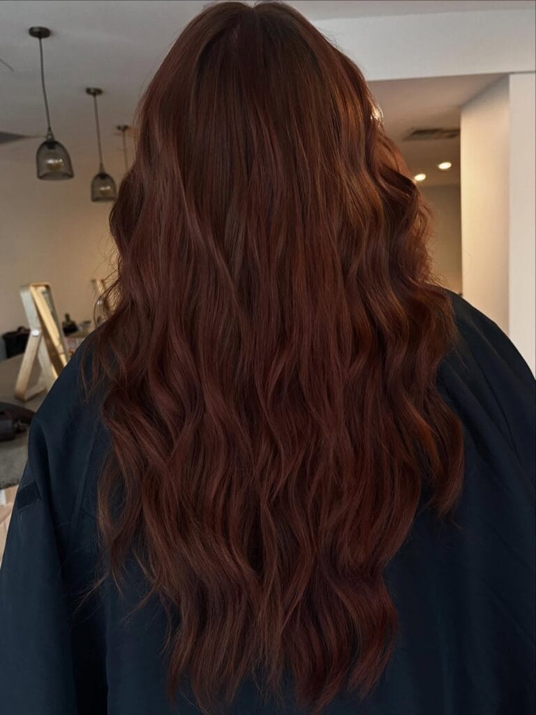 Long auburn hair styled in loose soft waves with natural movement.