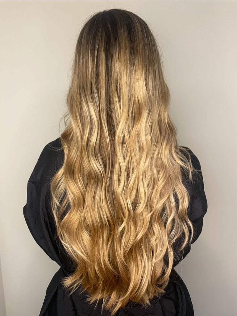 Very long honey blonde hair with smooth flowing waves and a warm blended color.