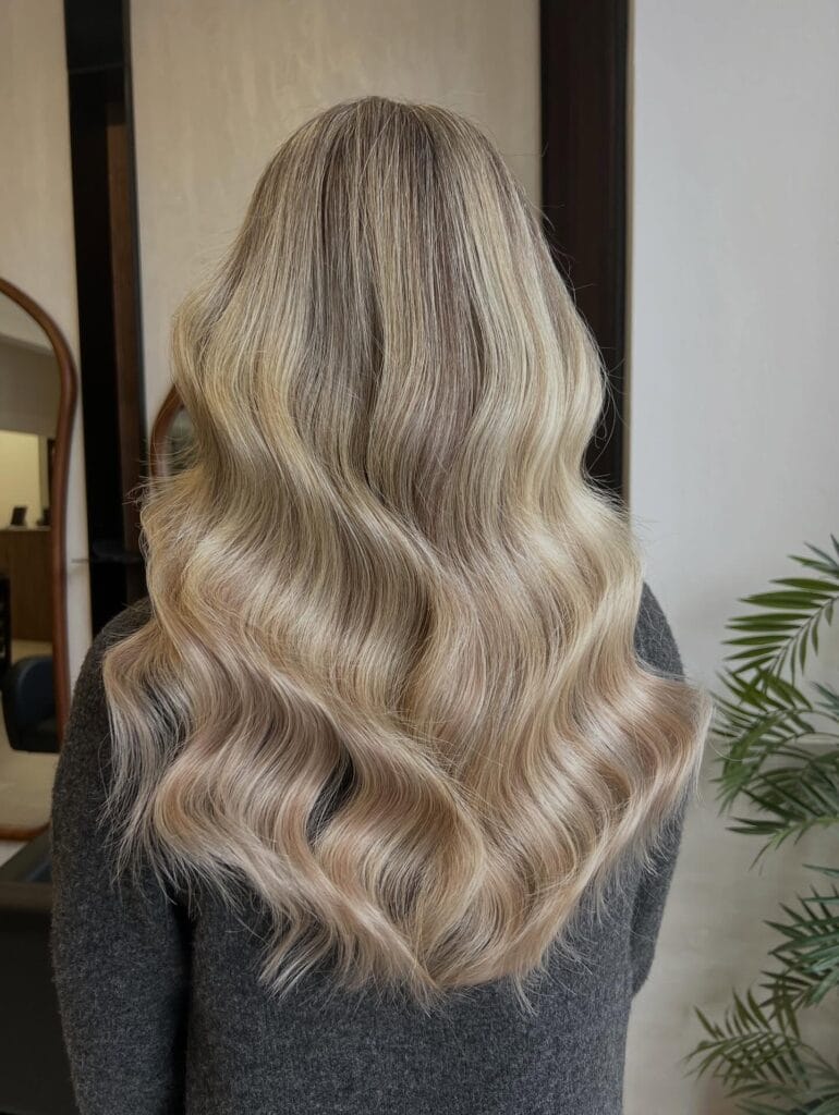 Long beige blonde hair with soft waves and subtle natural volume.