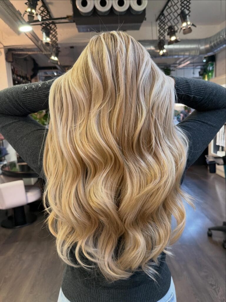 Long golden blonde hair with voluminous defined waves and a full body shape.