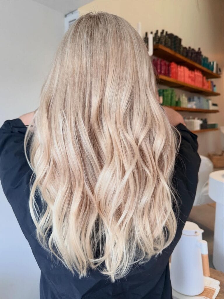 Long platinum blonde hair with loose waves and a natural lived in texture.