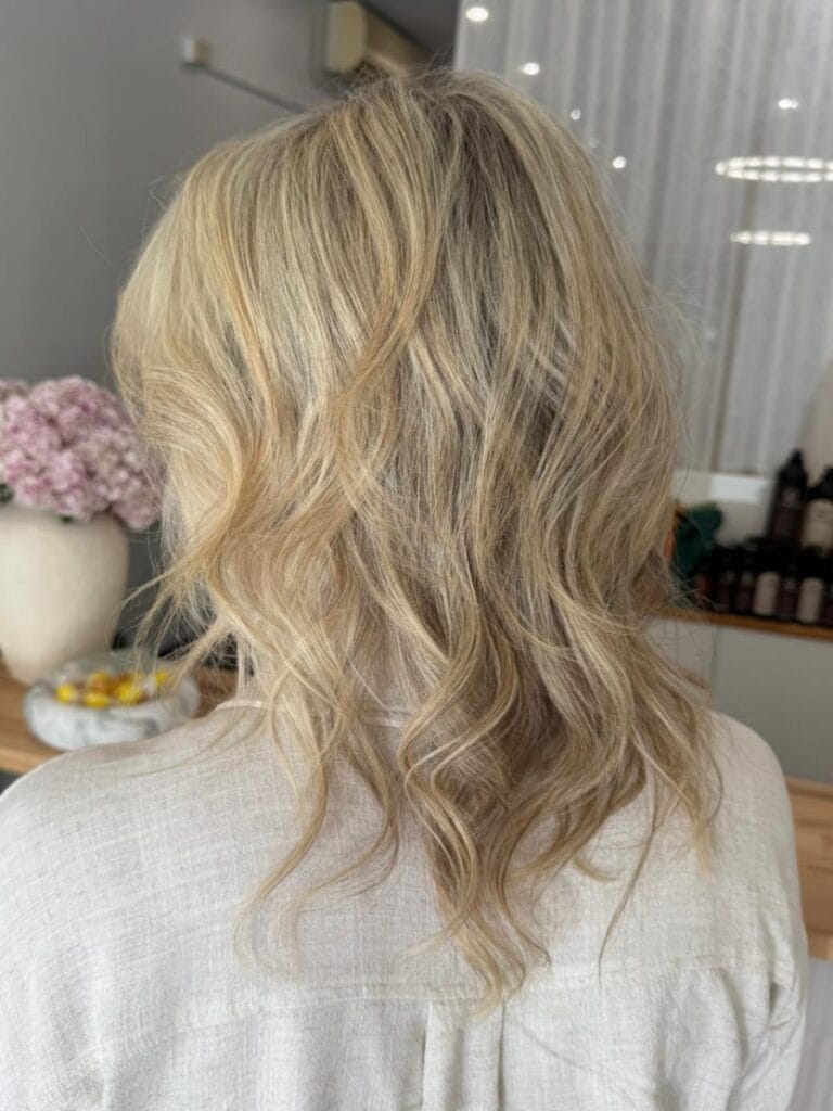 Shoulder length blonde hair with soft loose waves and light airy layers.