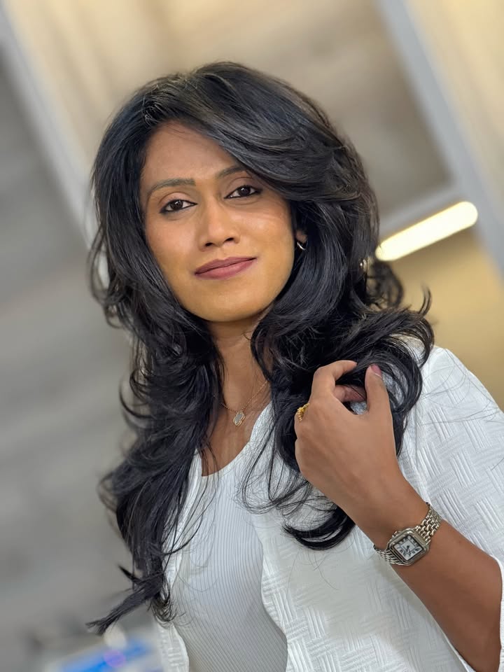 Shoulder length dark layered hair with side swept bangs and voluminous movement.