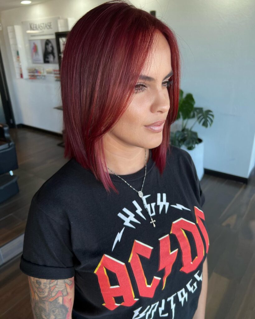 A woman wearing a sleek straight shoulder length lob in a vibrant deep cherry red color.