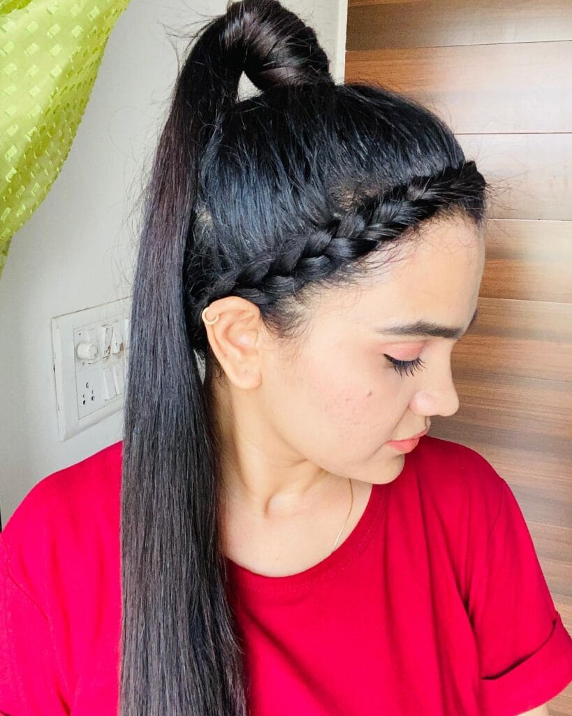 A young woman with long dark hair styled in a high, sleek ponytail with a decorative side braid along the hairline.