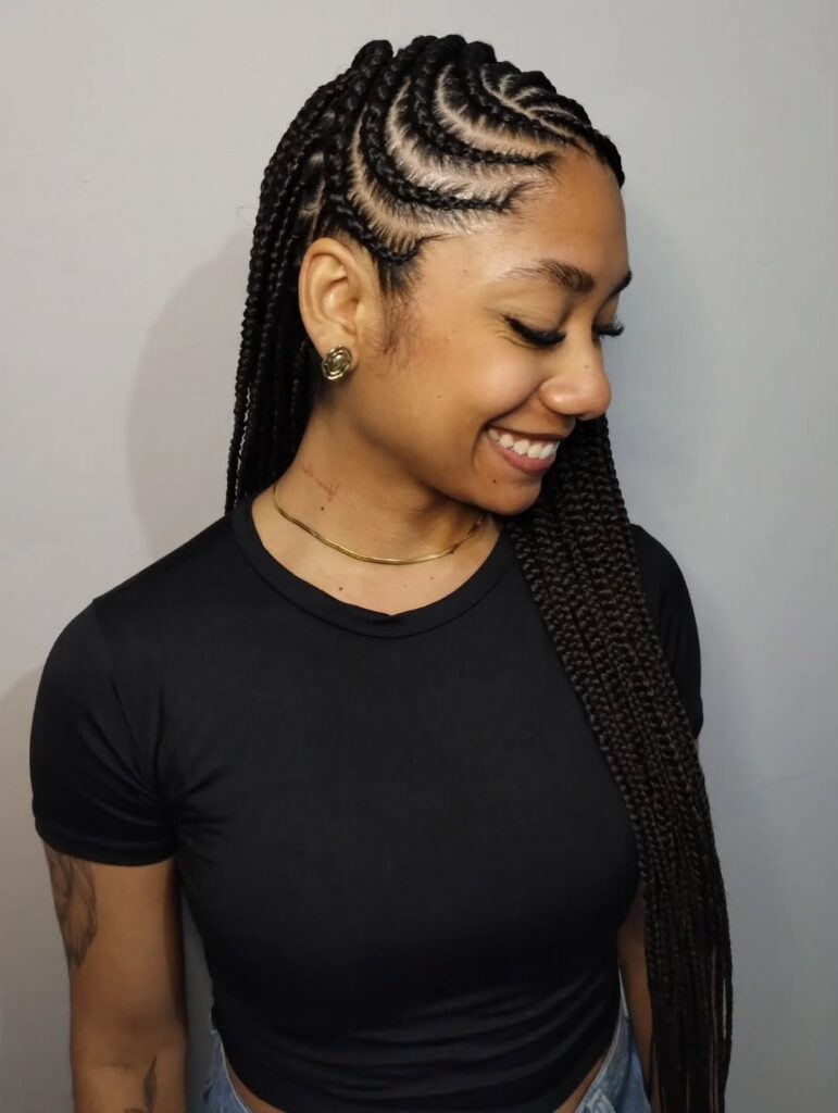 A woman smiling while showcasing dark Fulani braids with a beautiful wavy cornrow pattern on the side of her head.