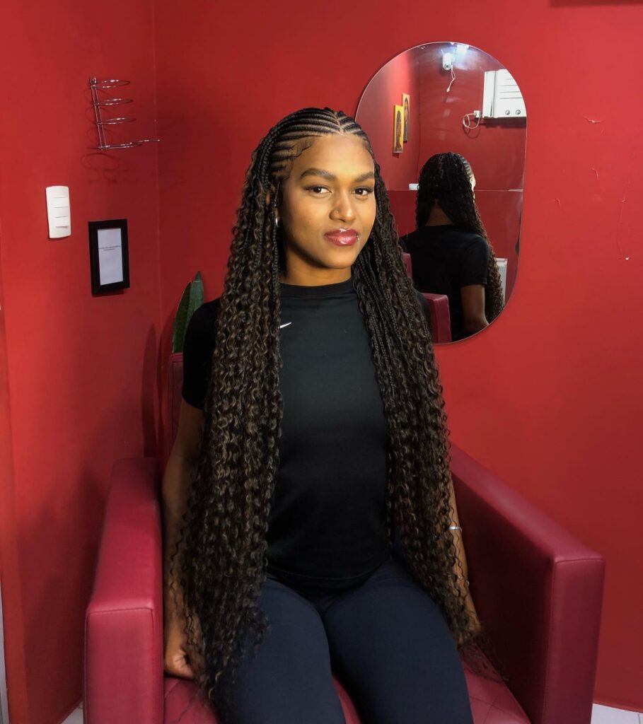 A woman with long mixed brown Fulani braids that have beautiful wavy ends cascading over her shoulders.