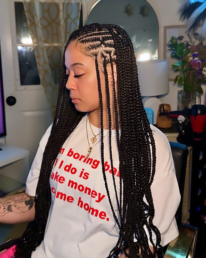 A woman with long black Fulani braids featuring an intricate criss cross geometric pattern on the side of her head.