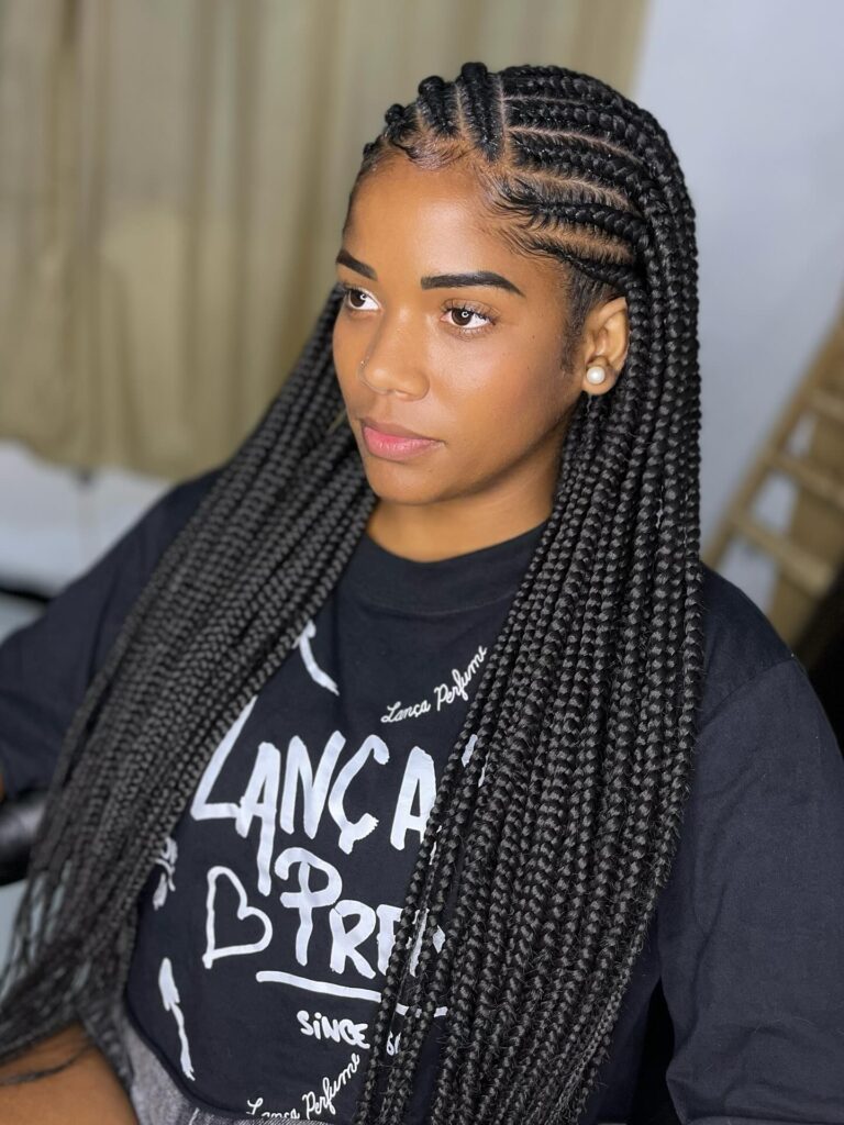 A woman looking to the side wearing sleek black Fulani braids with precise diagonal cornrows and neatly laid edges.