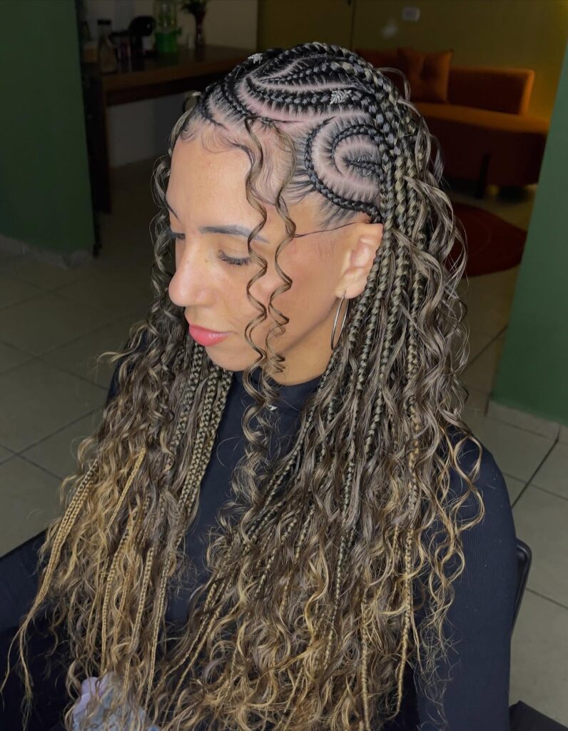 A woman showing off long honey blonde Fulani braids with a unique spiral cornrow design on the side and loose curly strands.