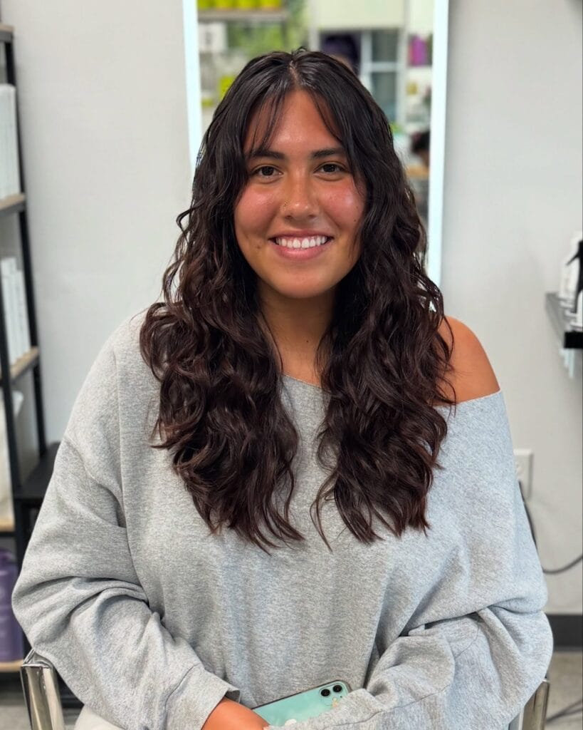 Long dark wavy hair with natural curls and a center part.