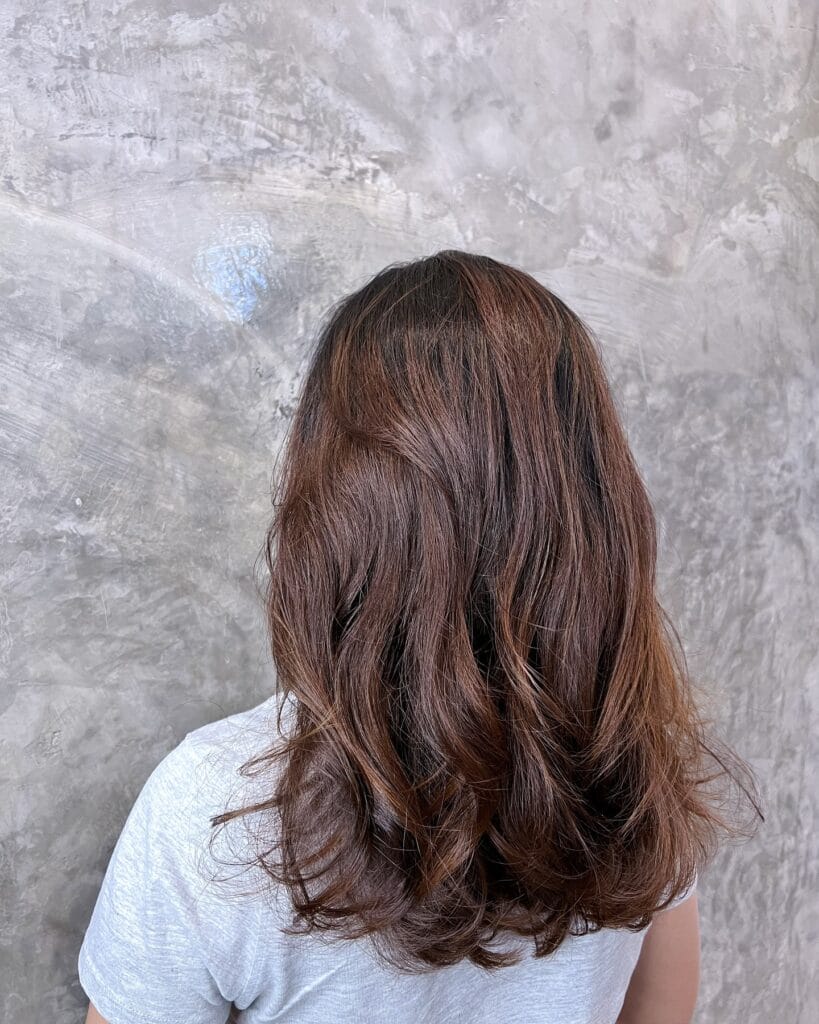 Long brunette hair with soft layered waves and natural volume through the ends.