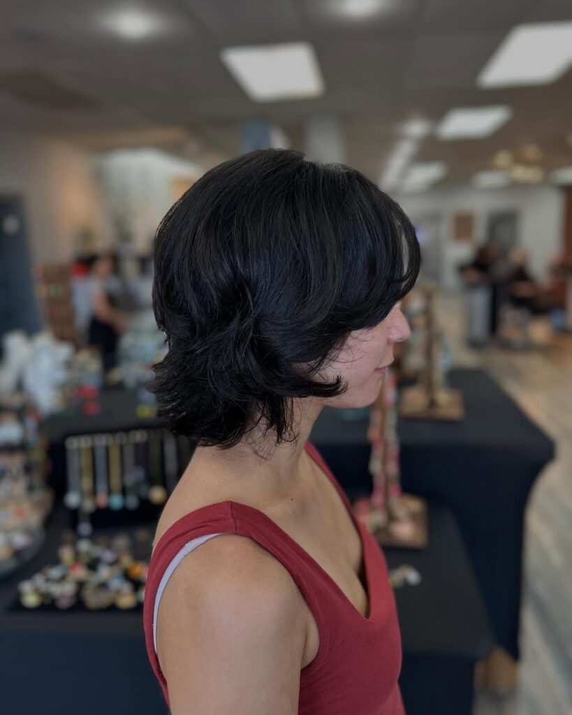 A medium length layered tomboy shag haircut with soft flicked ends and natural dark brunette color.
