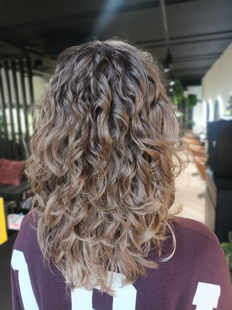 Medium-length wavy hair with beachy texture and soft highlighted tones.