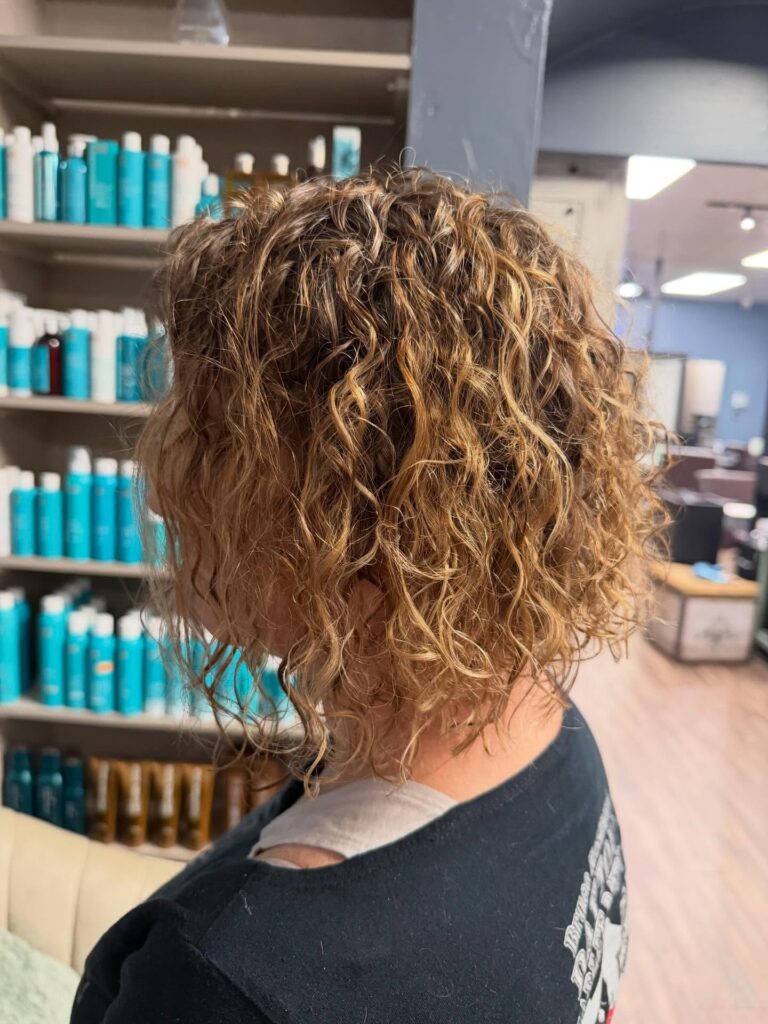 A woman with a short curly lob featuring defined curls and a rounded shape.