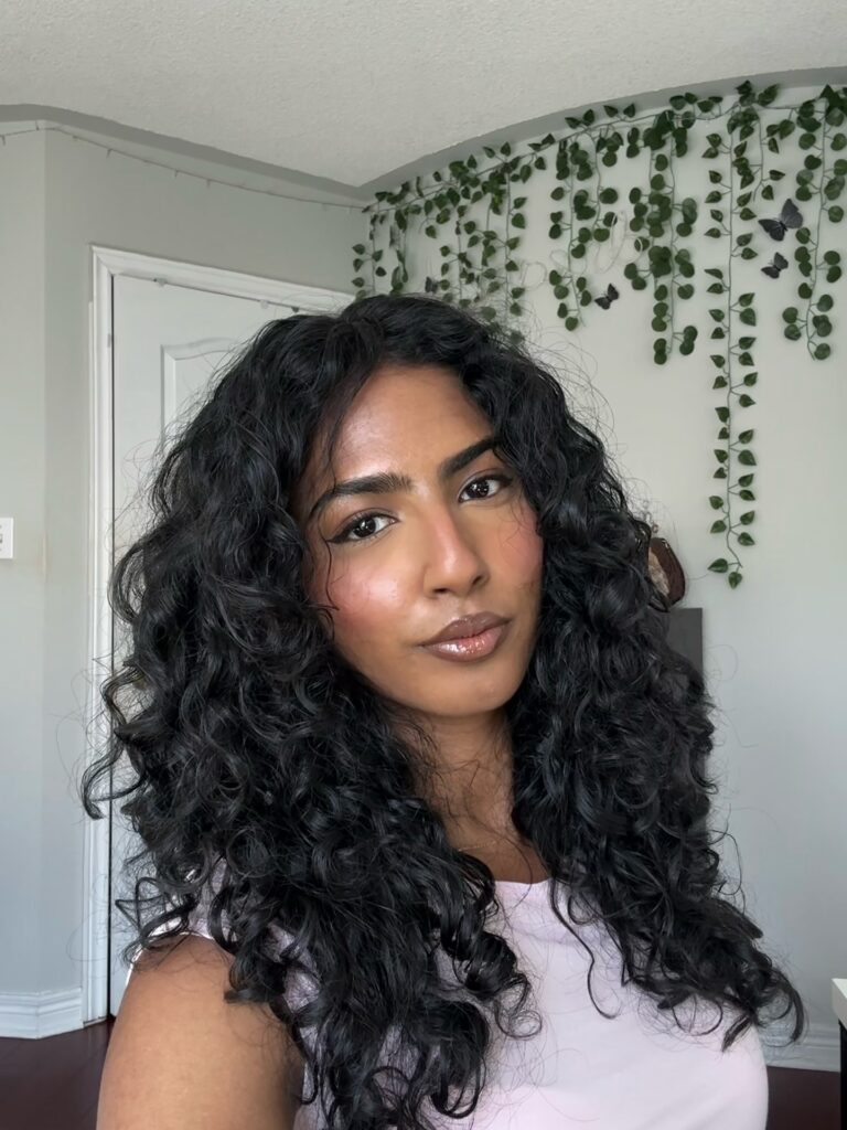 A woman with long layered curly hair featuring natural volume and defined curls.