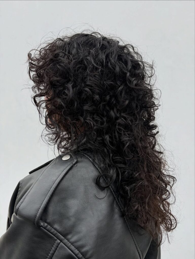 A woman with a layered curly shag haircut with natural volume and defined texture.