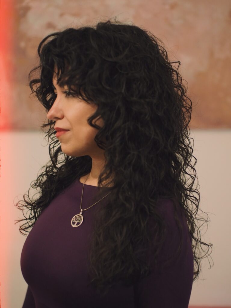 Long dark curly hair with layers and a side part, styled with natural definition and volume.