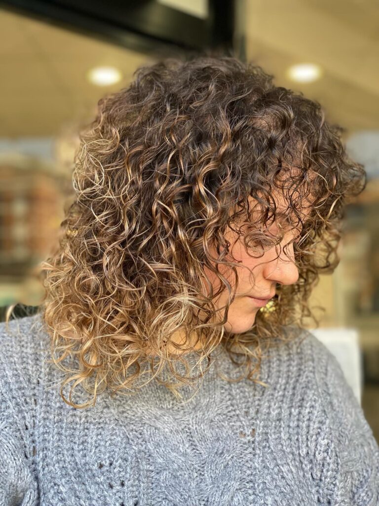 Medium length curly shag haircut with soft layers and natural textured curls.