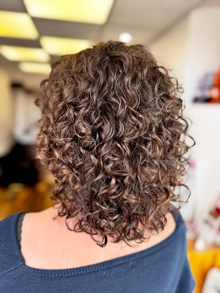 A woman with a defined curly bob featuring tight curls and a soft rounded shape.