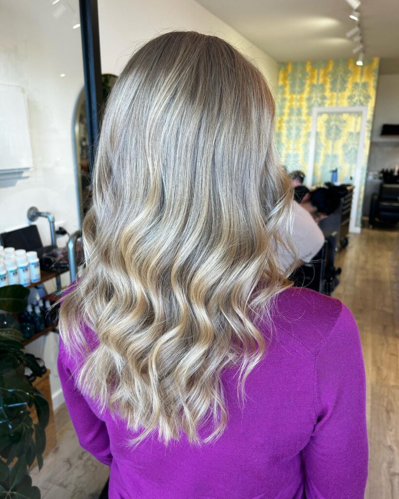 Long ash blonde hair styled in soft loose waves with cool tones.