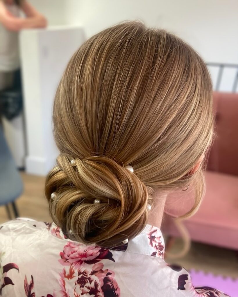 Blonde hair styled into a smooth low twisted bun at the nape.