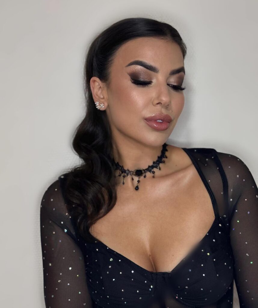 Long dark hair styled in sleek side swept waves with a glossy finish.