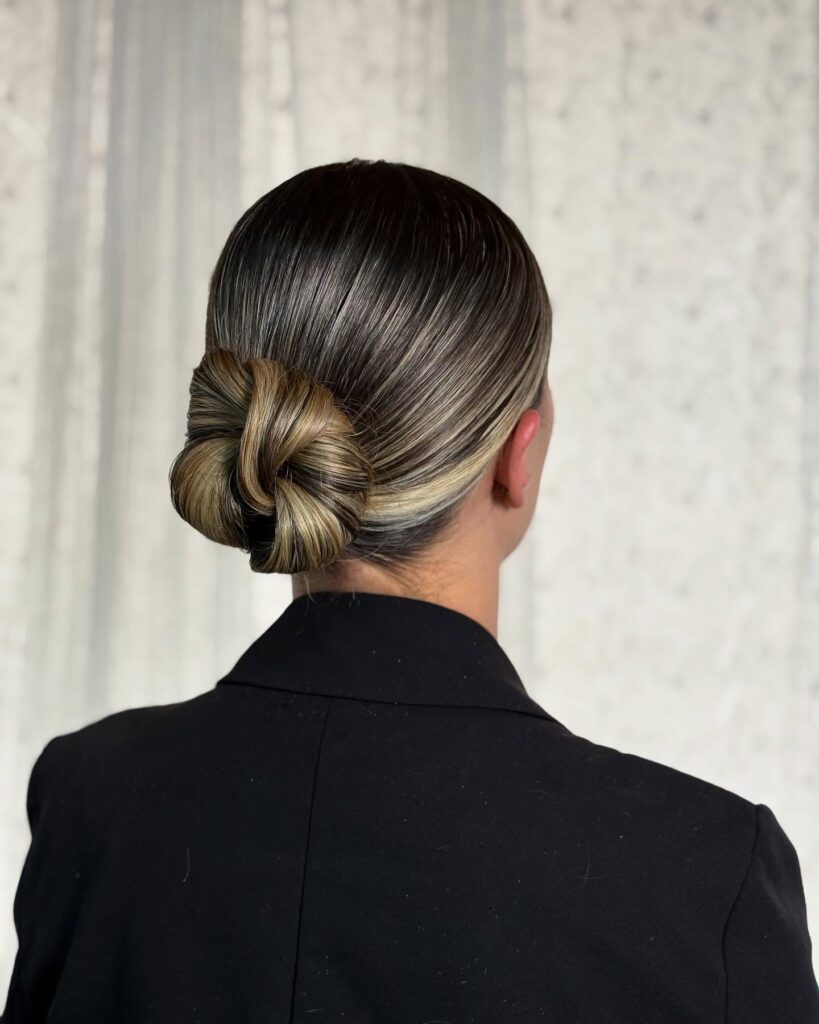 Sleek low knot with a smooth finish and a softly twisted tucked bun.