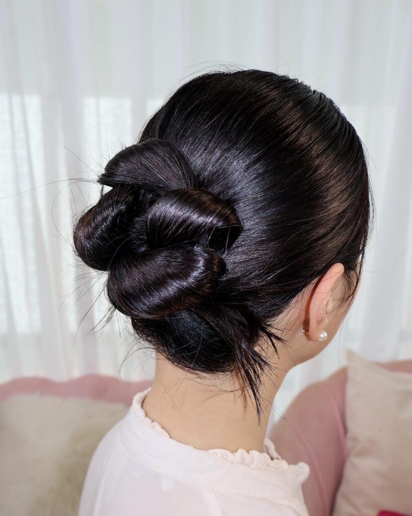 Dark hair styled into a glossy twisted bun with a sleek finish.