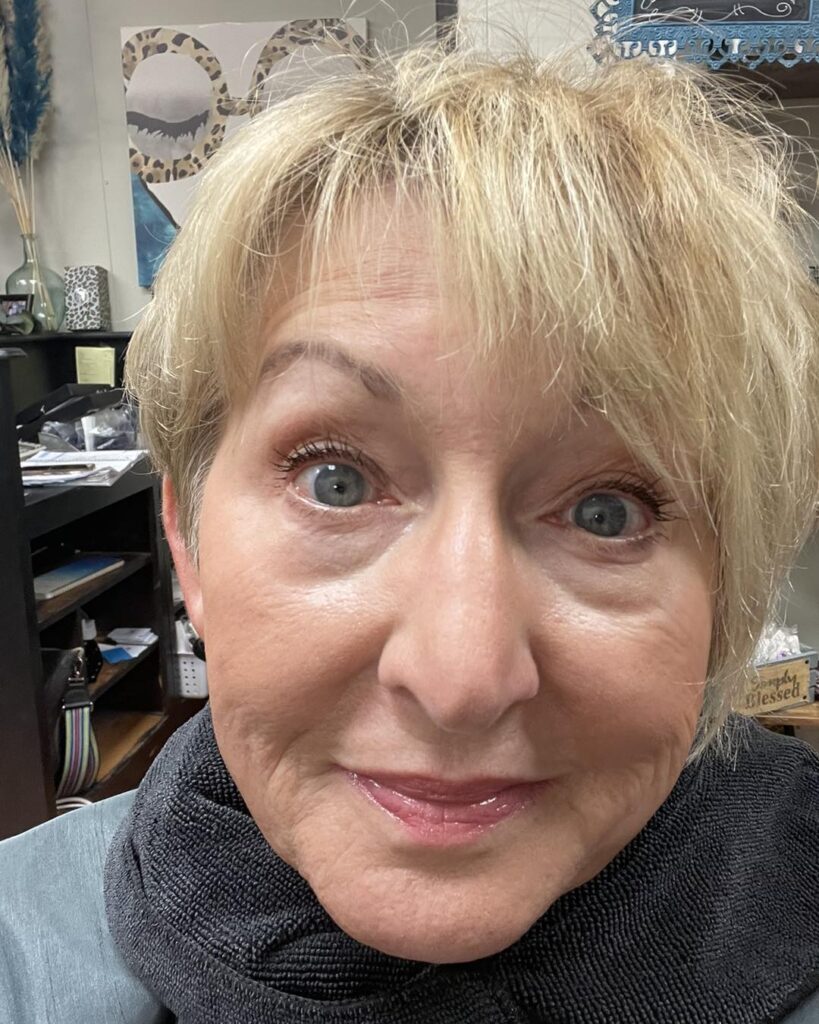 A woman with a short feathered pixie haircut and side swept bangs creating soft volume.