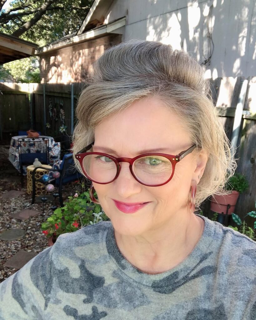 A woman with a textured gray updo and soft fringe creating volume at the crown.
