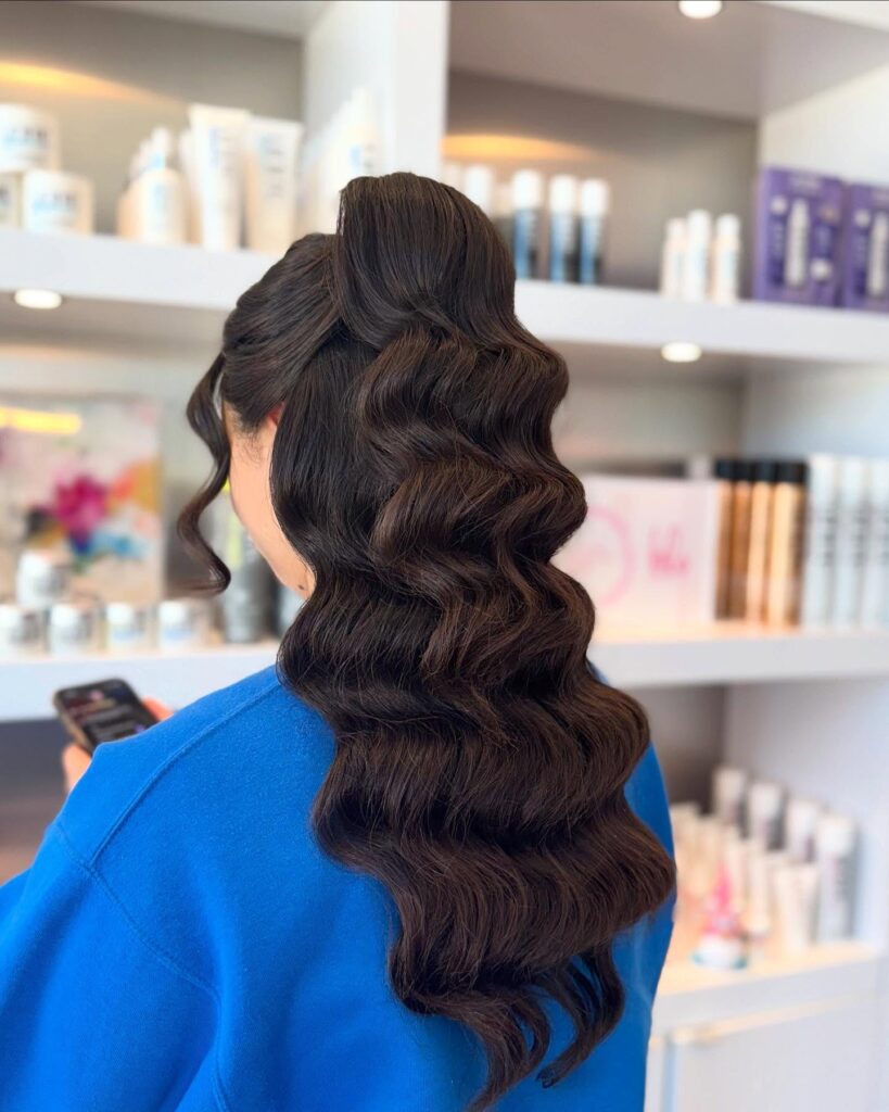 A woman from the back with long, dark brown hair styled in a uniform and highly defined vintage finger waves.