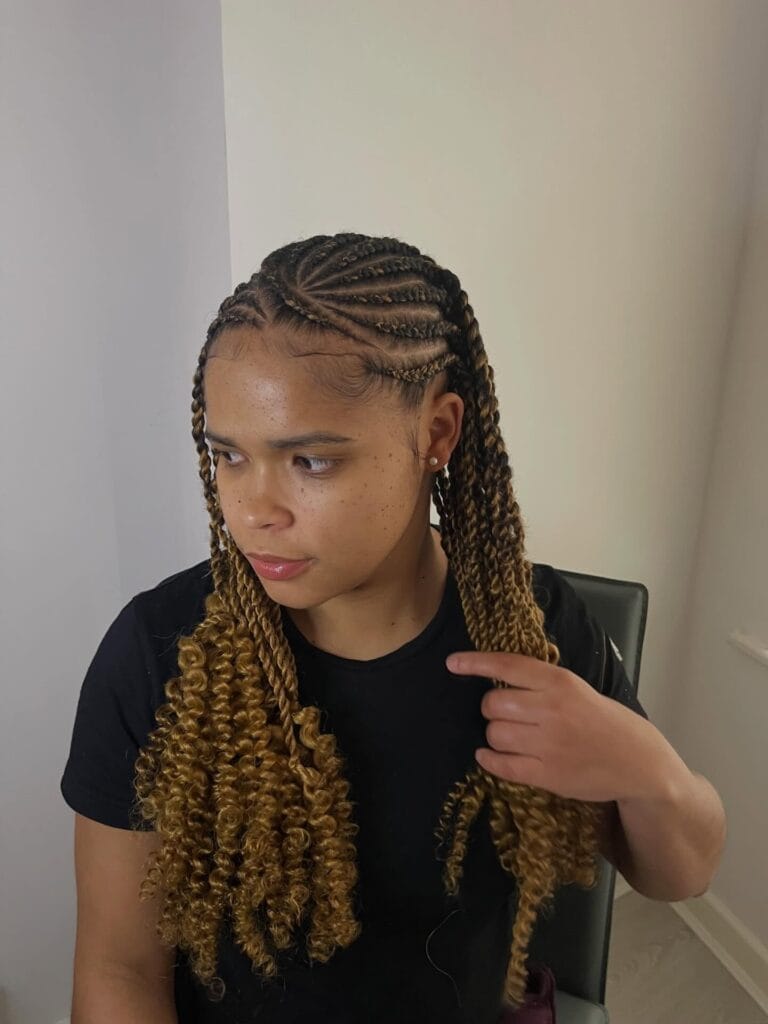 A young woman with neat curved cornrows and long golden blonde twists that transition into voluminous spiral curls at the ends.