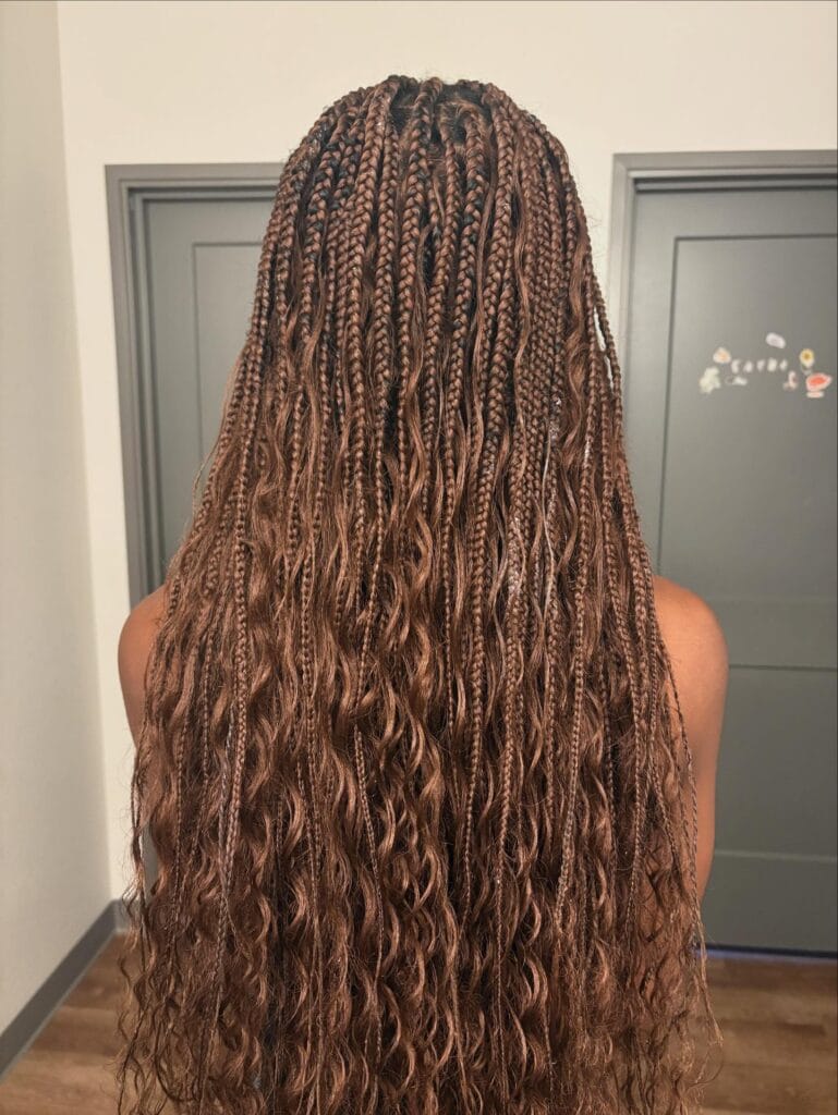 A back view shows a person with waist length auburn goddess box braids featuring wavy extensions for volume.