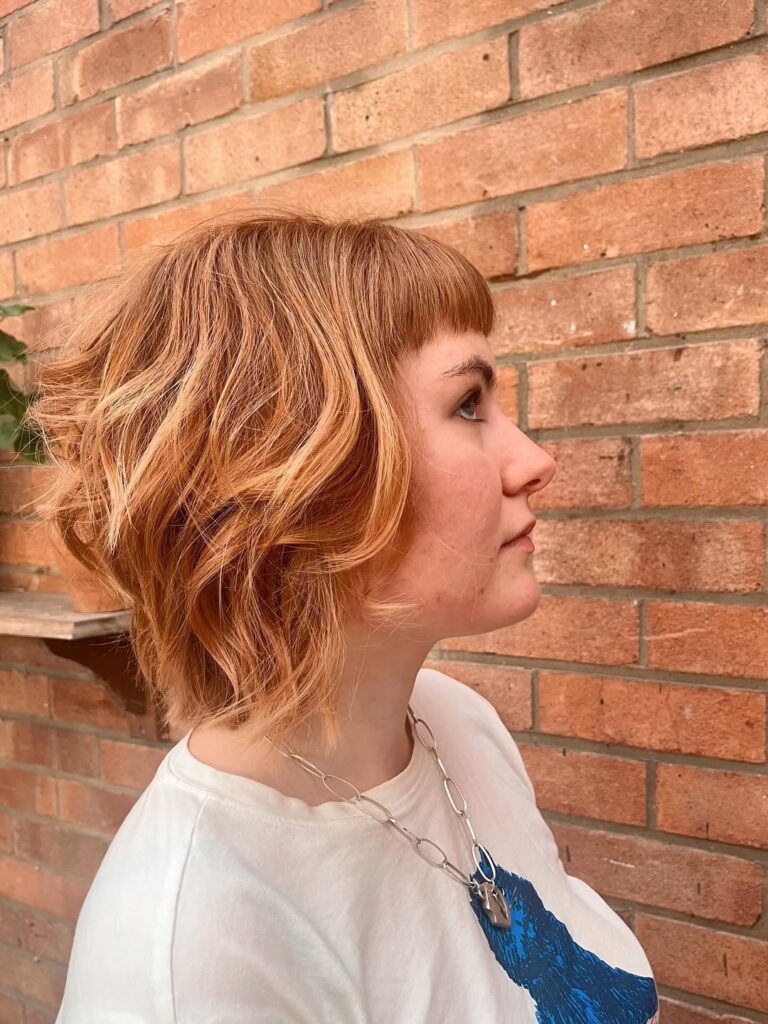 A woman with a copper wavy long bob featuring textured layers and soft movement.