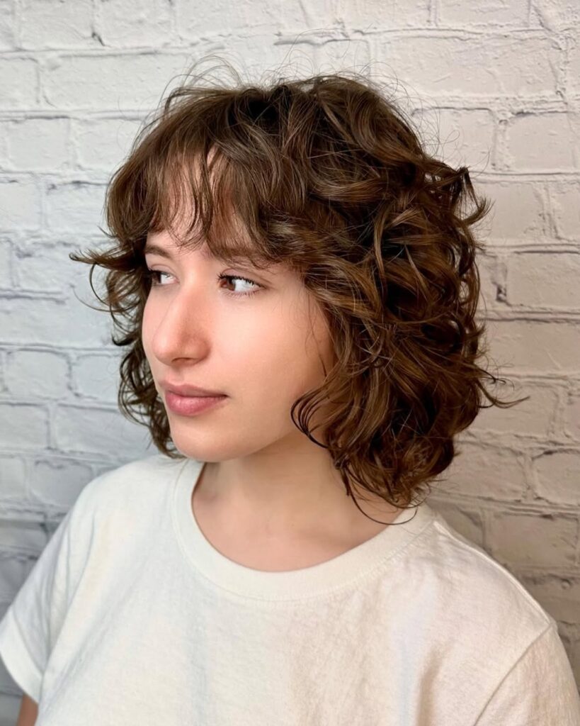 Short brown curly wavy bob with natural volume and soft layered texture.