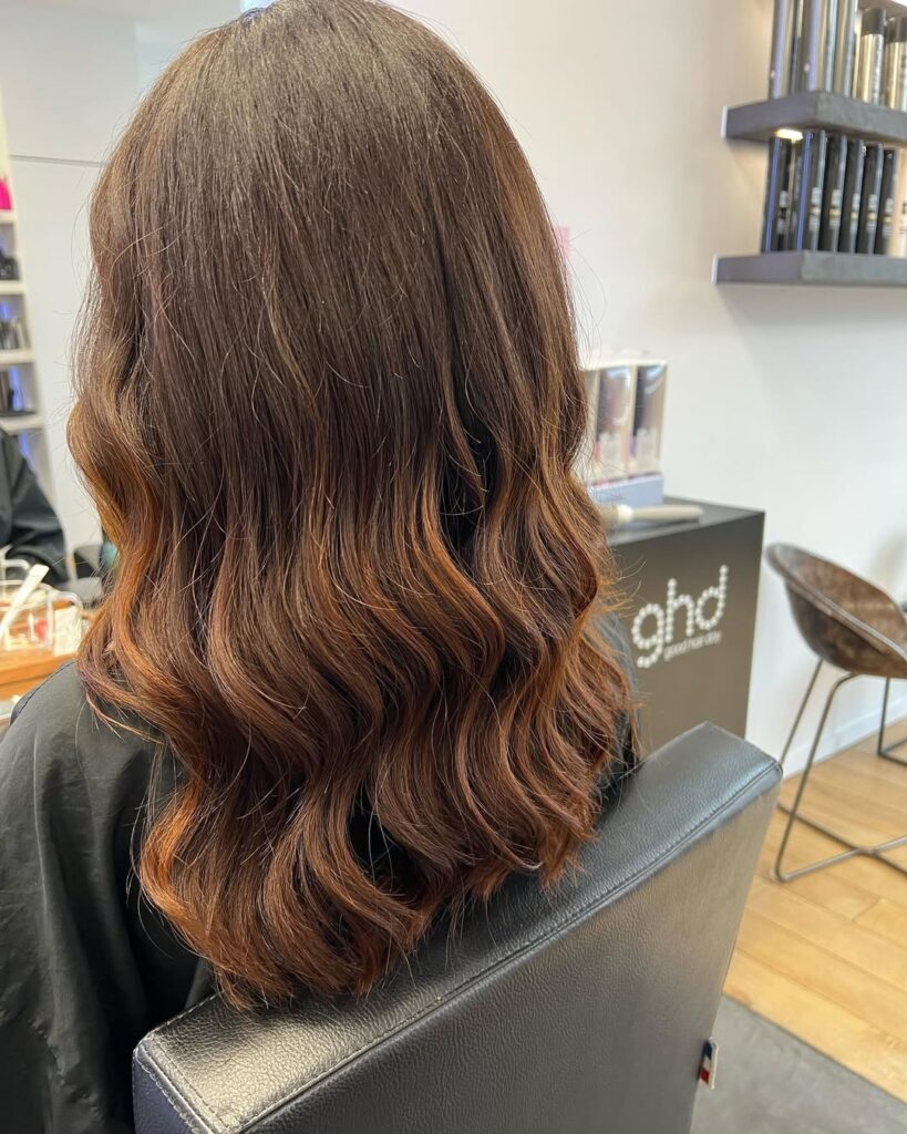 Long warm brown wavy hair with soft layers and natural movement from the back.