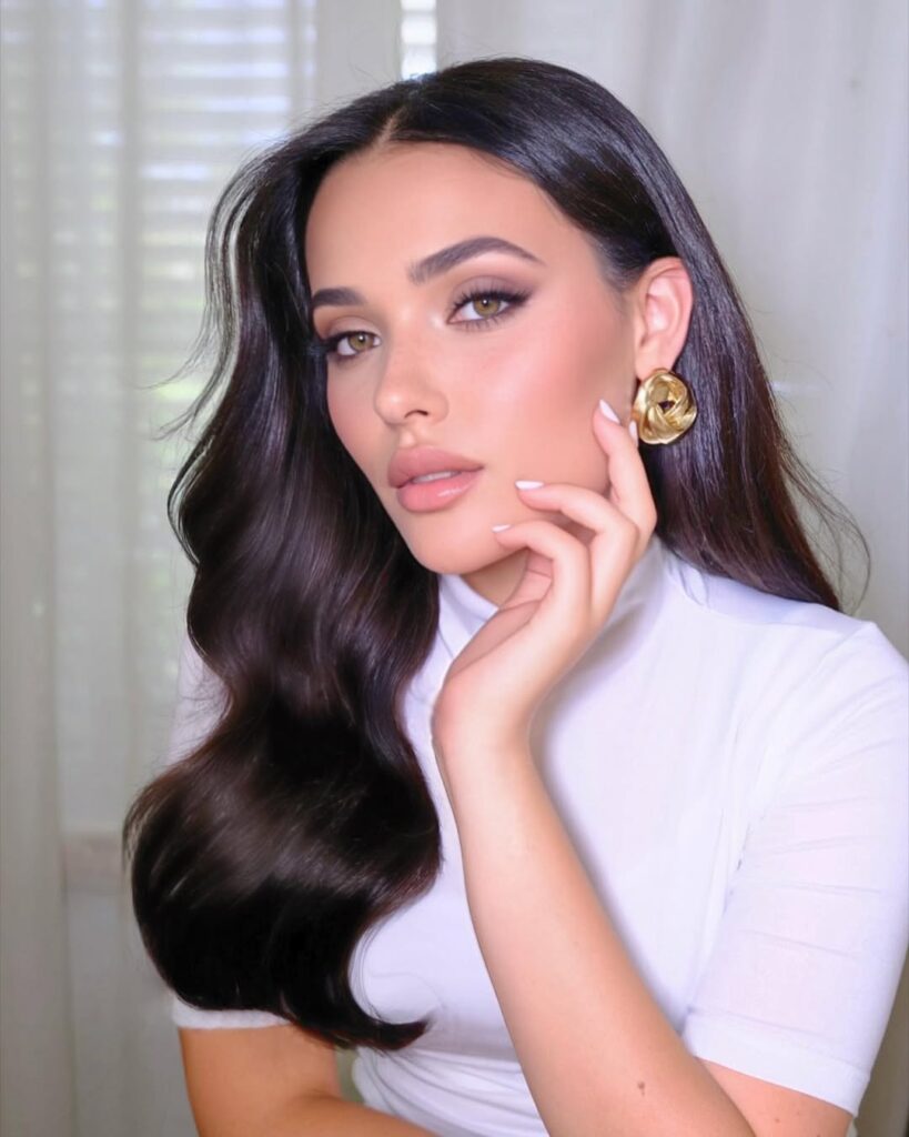 Long dark brunette wavy hair with a sleek glossy finish and soft defined waves.