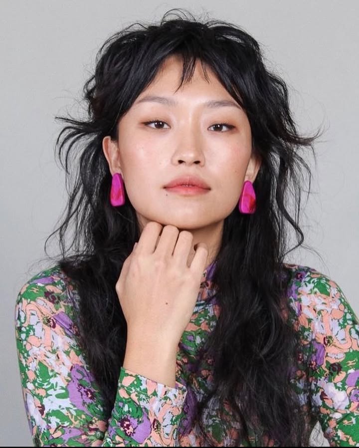 Long layered shag haircut with choppy bangs and textured dark hair.