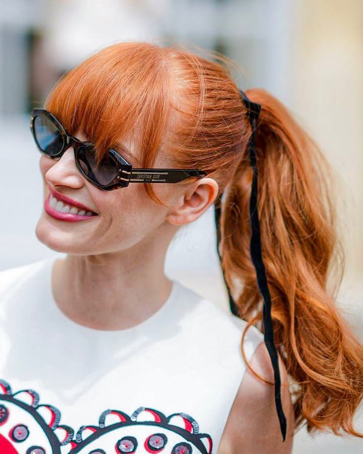 Long copper hair in a high ponytail with blunt bangs and sleek finish.