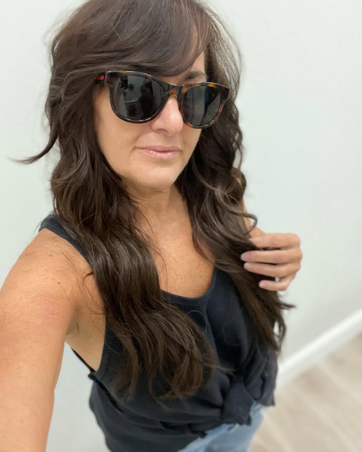 Long brunette layered hair with soft curtain bangs and smooth movement.