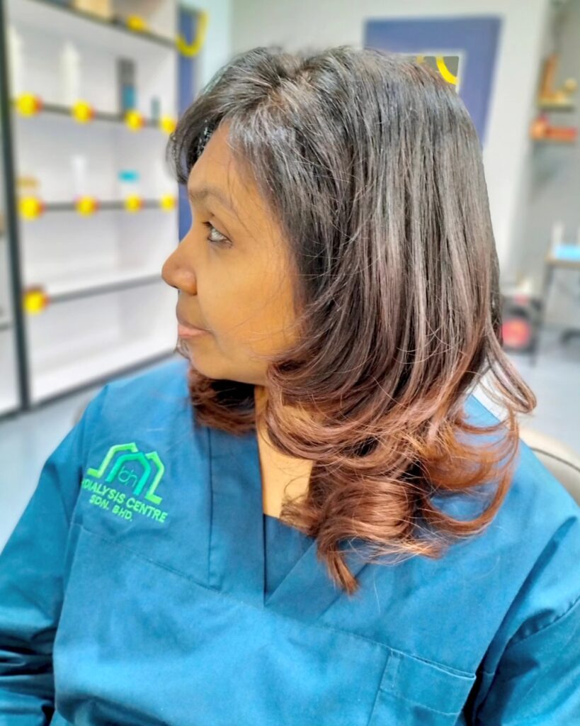 A woman with medium-length dark hair fading into mahogany ombré with ends curled inward.