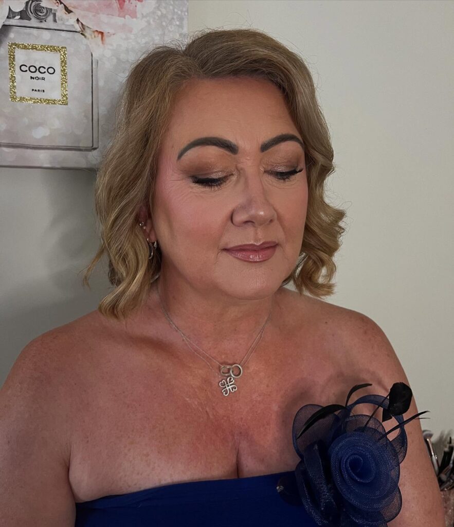 A woman with shoulder-length sandy blonde hair styled in soft, elegant waves and a side part.