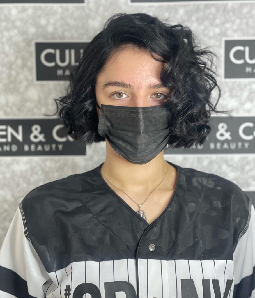 A person with a chin-length midnight black bob styled in glossy side-swept waves.