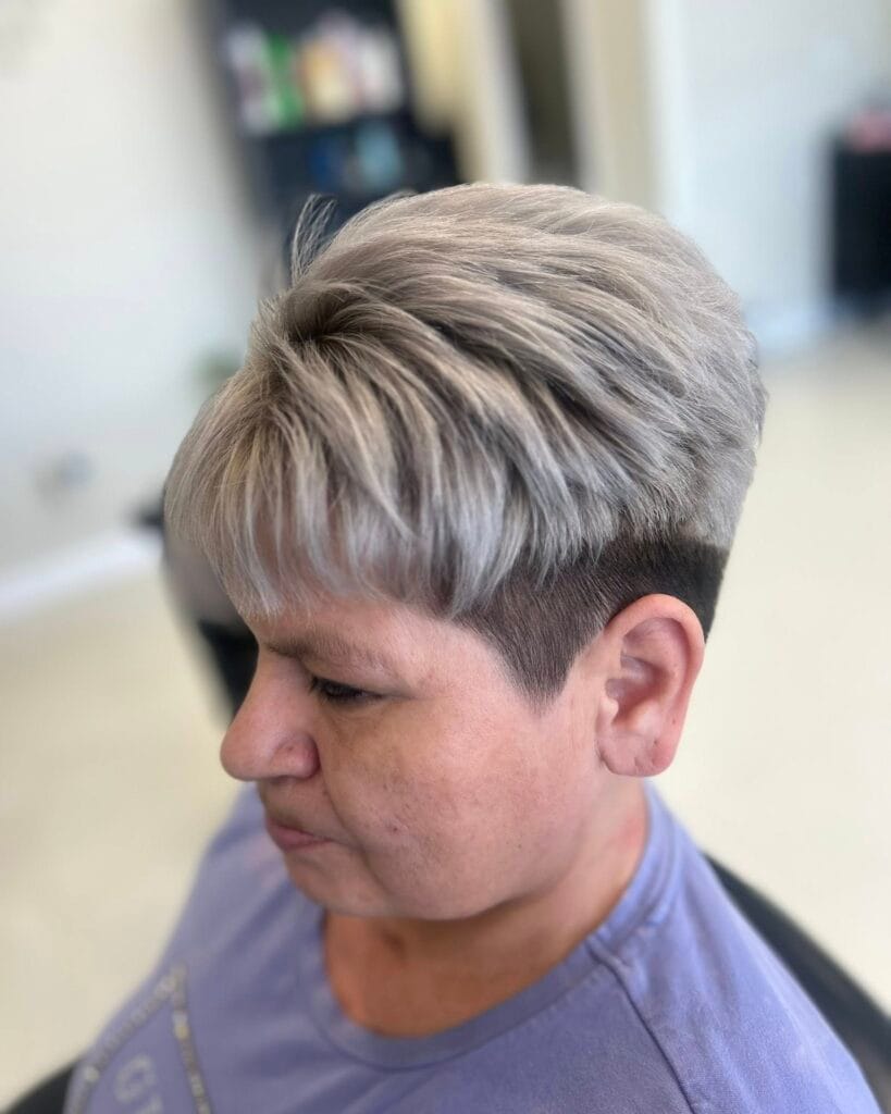 A woman with a two-tone pixie cut featuring a textured silver top and a dark buzzed undercut.