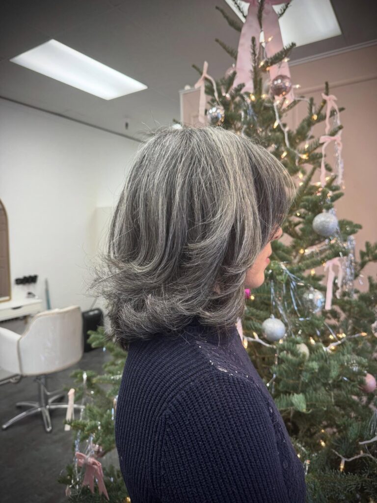 A layered bob with ash toned highlights, rounded volume, and softly blended bangs.