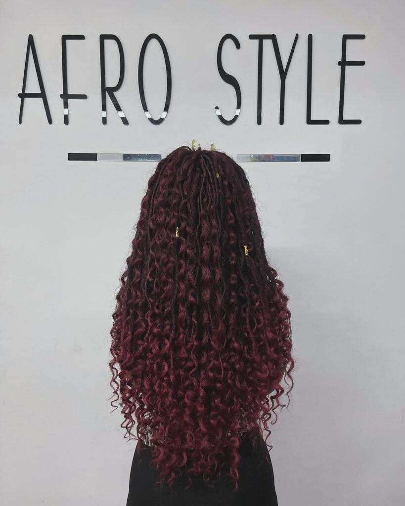 Long burgundy curly hairstyle with defined ringlets and full textured length.