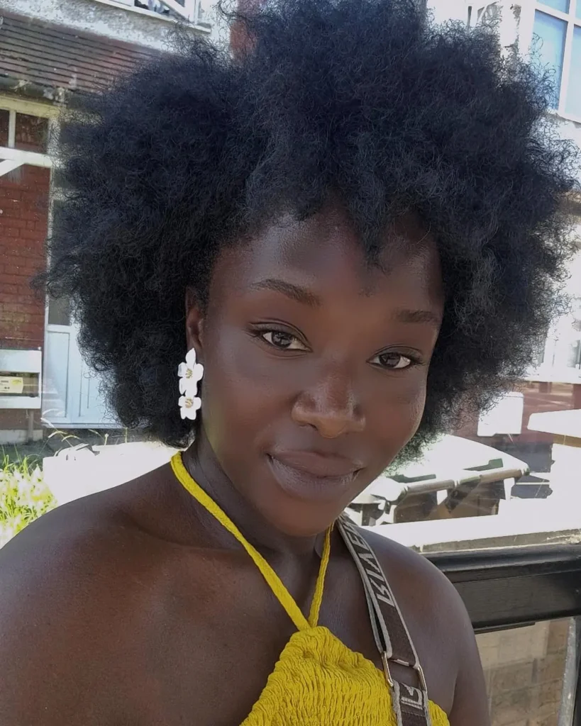 Full natural afro with soft volume and visible coily texture framing the face.